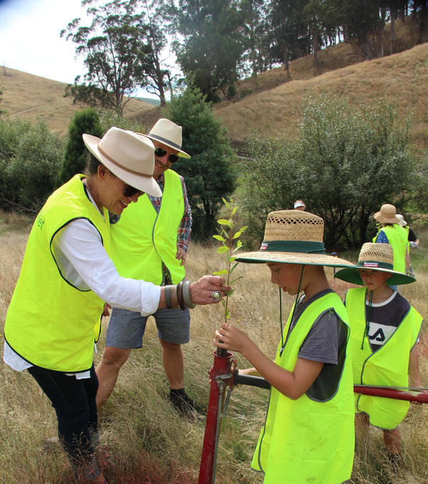 Martin and Rebeka shows a young boy how to plant a seedling.